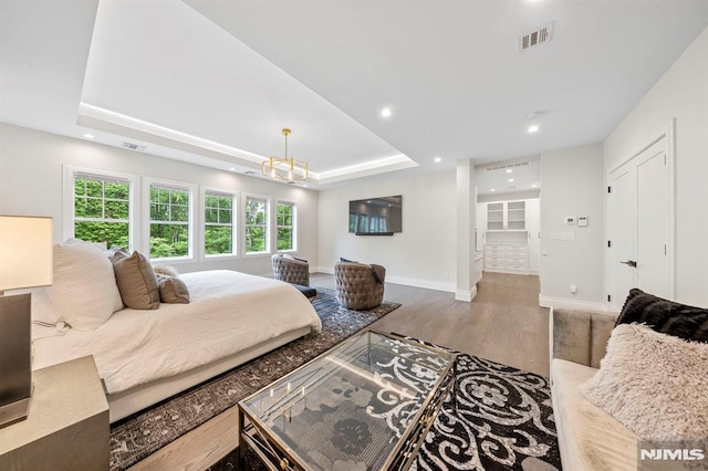 bedroom featuring a chandelier, hardwood / wood-style floors, and a raised ceiling