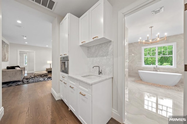 kitchen featuring light stone counters, dark wood-type flooring, sink, white cabinets, and oven