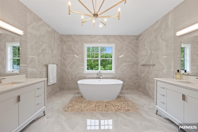 bathroom with a tub to relax in, vanity, tile walls, and a notable chandelier