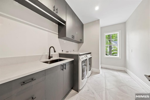 kitchen with washing machine and clothes dryer, gray cabinetry, and sink