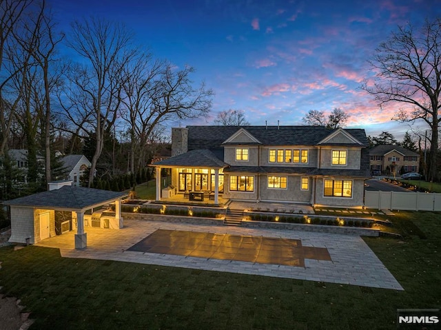 back house at dusk featuring a patio area, a yard, and a pool