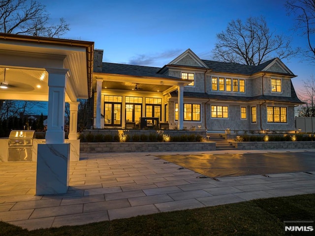 back house at dusk with a patio area and an outdoor kitchen