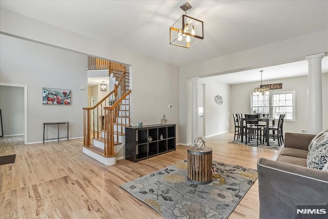 living room featuring ornate columns, hardwood / wood-style floors, and a notable chandelier