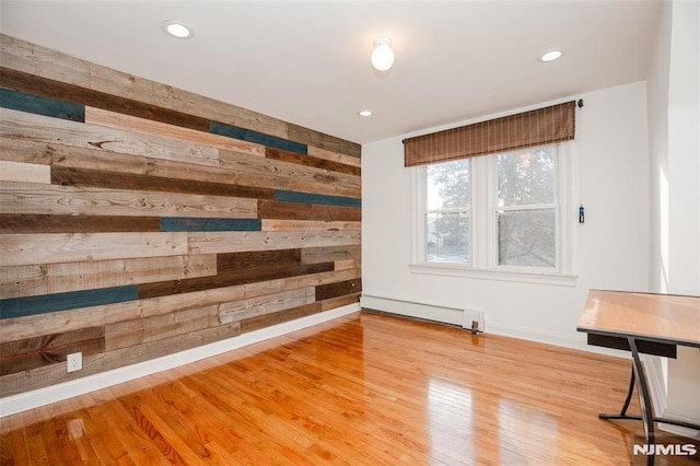 unfurnished room with wood-type flooring, wooden walls, and baseboard heating