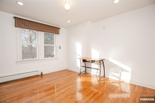 empty room with hardwood / wood-style flooring and a baseboard heating unit