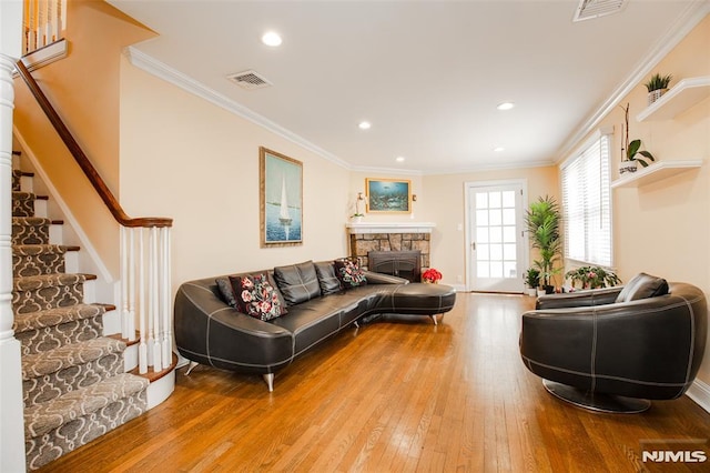 living room featuring crown molding, a fireplace, and wood-type flooring