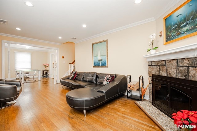 living room featuring a fireplace, ornamental molding, and light hardwood / wood-style floors