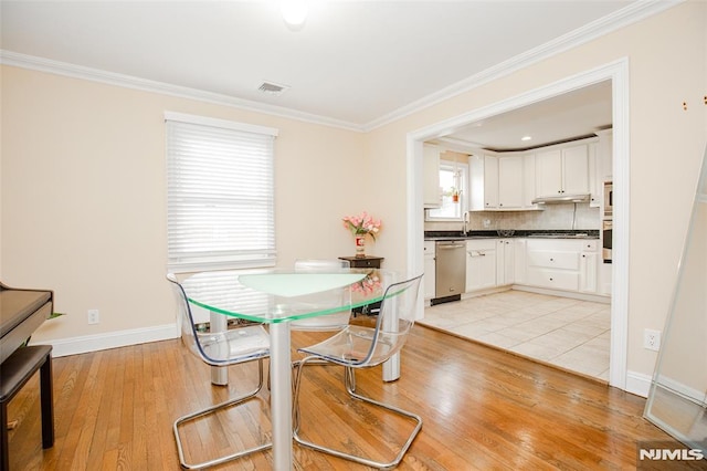 dining room with light wood-type flooring and crown molding