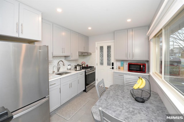 kitchen with decorative backsplash, stainless steel appliances, sink, white cabinetry, and light tile patterned flooring