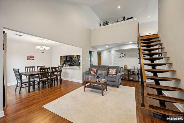 living room featuring a notable chandelier, wood-type flooring, and high vaulted ceiling