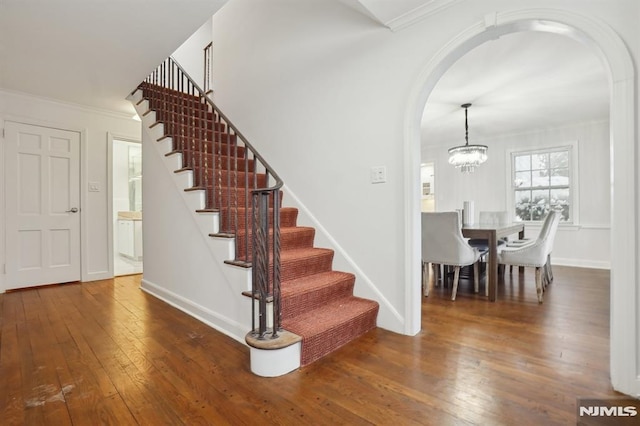 entryway with dark hardwood / wood-style floors, crown molding, and a chandelier