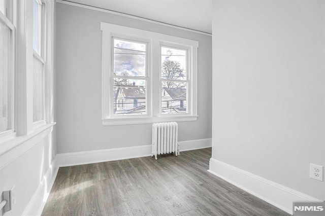 spare room with radiator heating unit and wood-type flooring