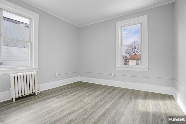 spare room featuring wood-type flooring, radiator, and ornamental molding