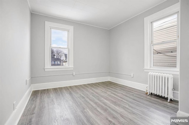 spare room featuring light hardwood / wood-style floors, radiator, and ornamental molding