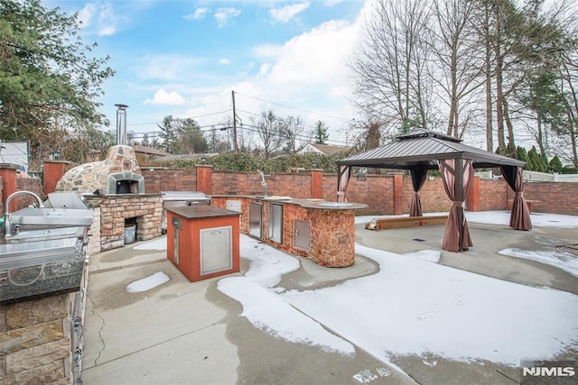 view of patio featuring a gazebo, exterior kitchen, and an outdoor stone fireplace