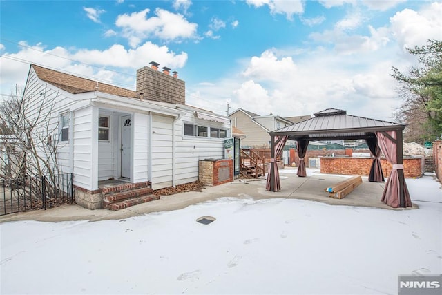 snow covered rear of property with a gazebo