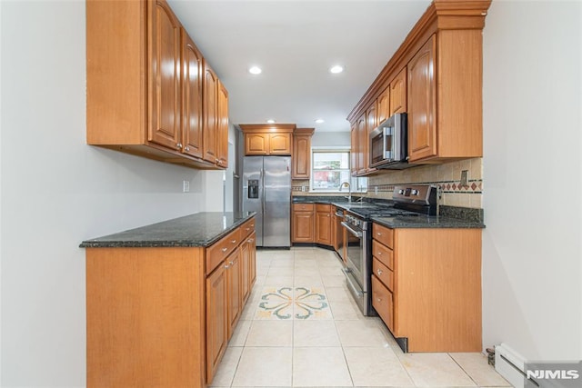 kitchen featuring stainless steel appliances, dark stone counters, light tile patterned flooring, sink, and backsplash