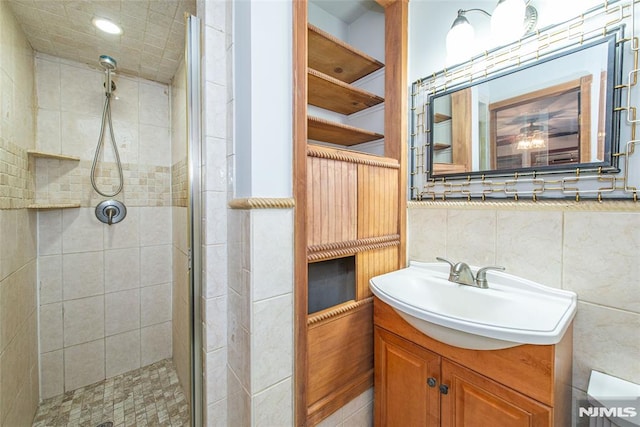 bathroom with tile walls, a shower with door, tasteful backsplash, and vanity