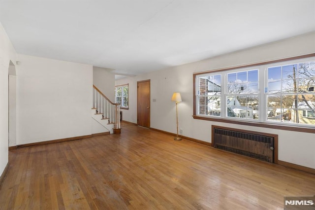 unfurnished living room featuring radiator heating unit and light hardwood / wood-style floors