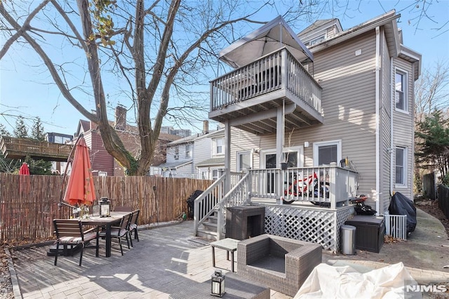 rear view of property with a balcony, a patio, a fire pit, and a deck