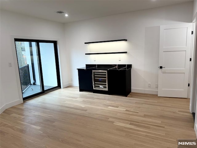 bar with wine cooler and light hardwood / wood-style floors