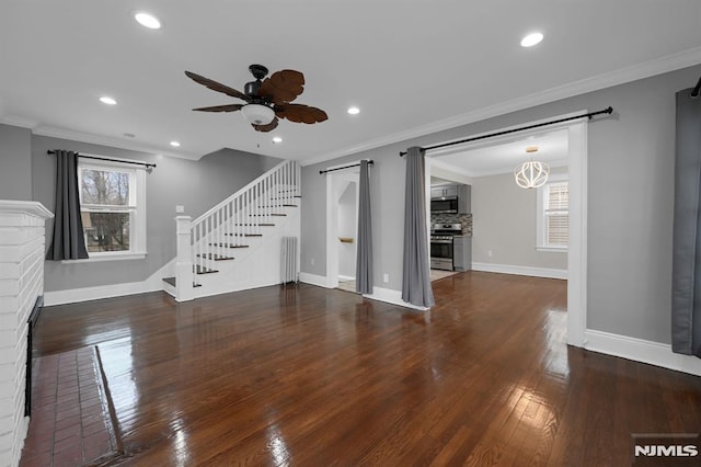 unfurnished living room with crown molding, ceiling fan with notable chandelier, and a brick fireplace