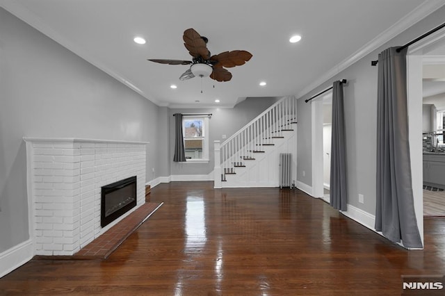 unfurnished living room featuring dark hardwood / wood-style flooring, crown molding, a fireplace, and ceiling fan