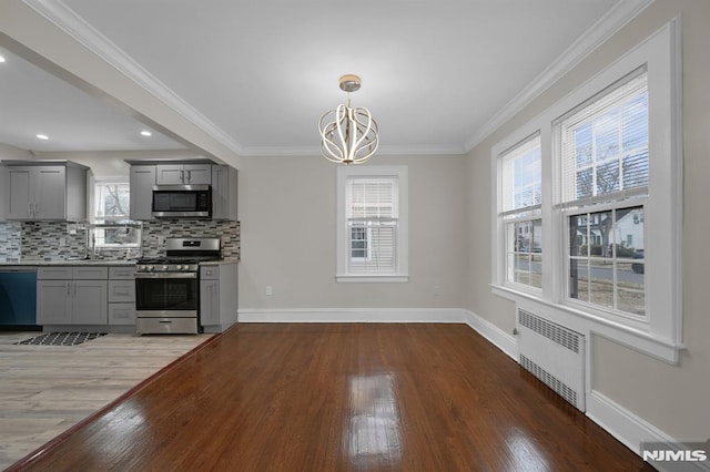 kitchen featuring tasteful backsplash, radiator, gray cabinets, and appliances with stainless steel finishes