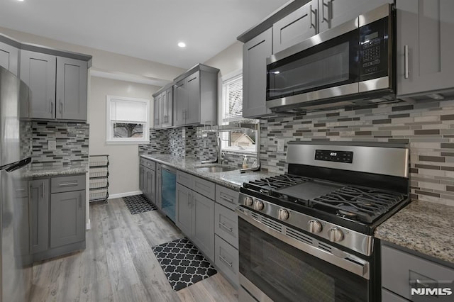 kitchen featuring sink, light stone countertops, stainless steel appliances, and tasteful backsplash