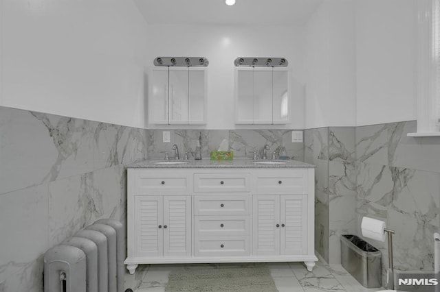 bathroom featuring radiator heating unit, vanity, and tile walls