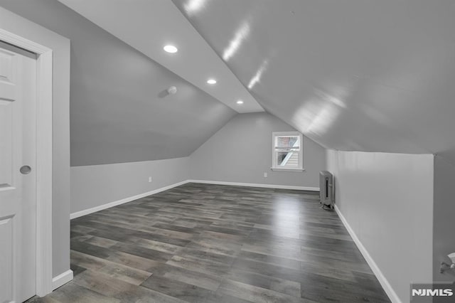 additional living space with radiator, lofted ceiling, and dark hardwood / wood-style floors