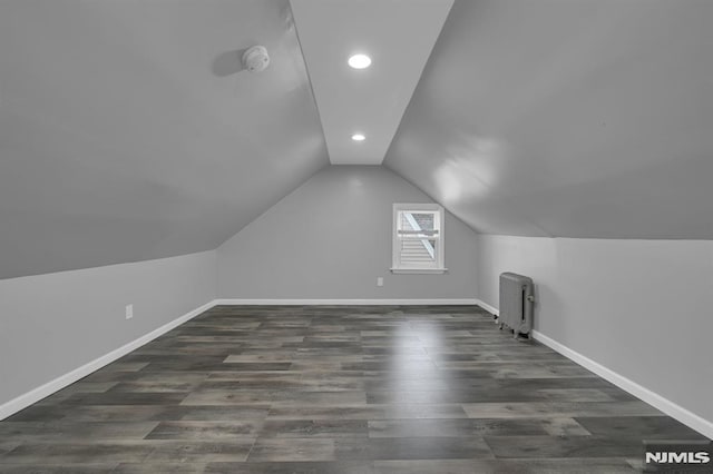 bonus room featuring vaulted ceiling, radiator, and dark wood-type flooring