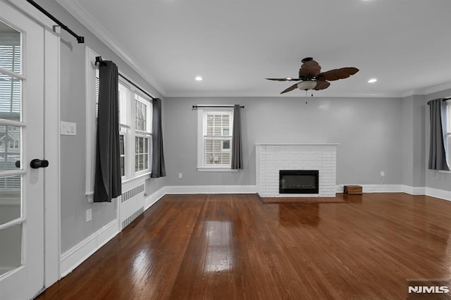 unfurnished living room with radiator, crown molding, ceiling fan, a fireplace, and dark hardwood / wood-style flooring