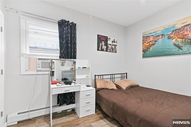 bedroom with cooling unit, light wood-type flooring, and a baseboard heating unit