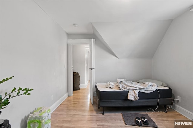 bedroom featuring lofted ceiling and light hardwood / wood-style flooring