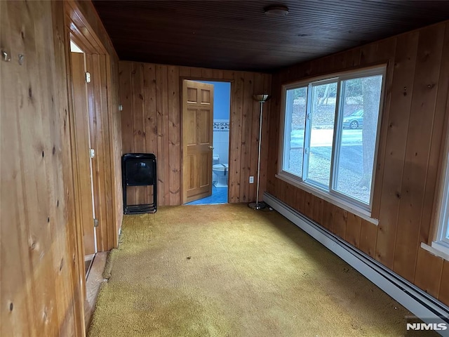 carpeted empty room with wooden ceiling, wood walls, and a baseboard radiator