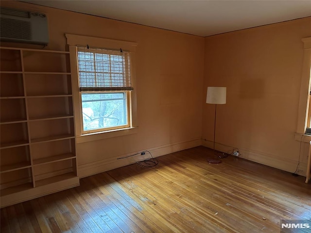 spare room featuring a wall mounted AC and hardwood / wood-style floors