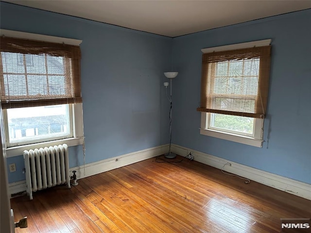 empty room featuring radiator and hardwood / wood-style floors