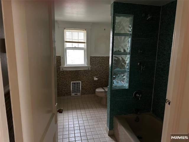 bathroom featuring tile walls, tiled shower / bath, tile patterned flooring, and toilet