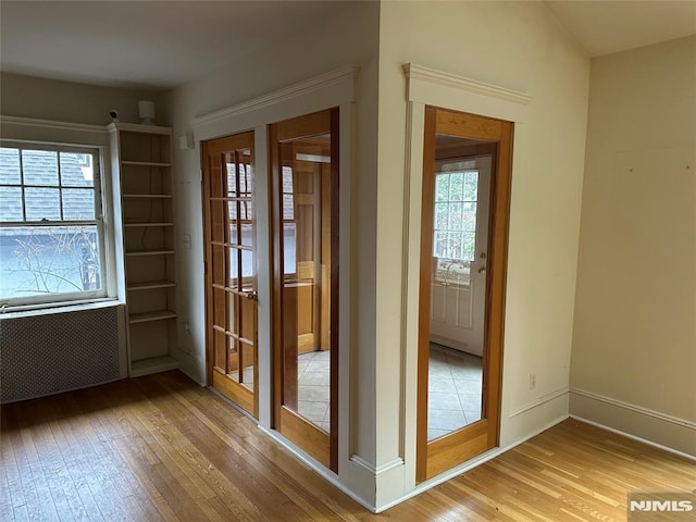 doorway to outside featuring light wood-type flooring, radiator, and a wealth of natural light