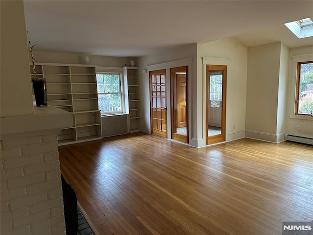 unfurnished living room featuring a skylight and light hardwood / wood-style floors