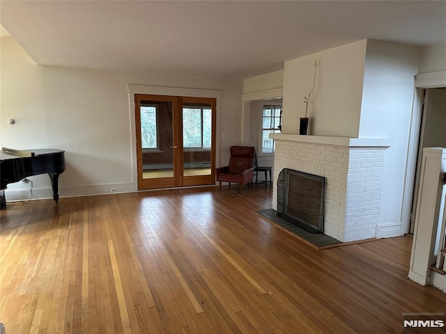 unfurnished living room featuring a brick fireplace and dark hardwood / wood-style floors