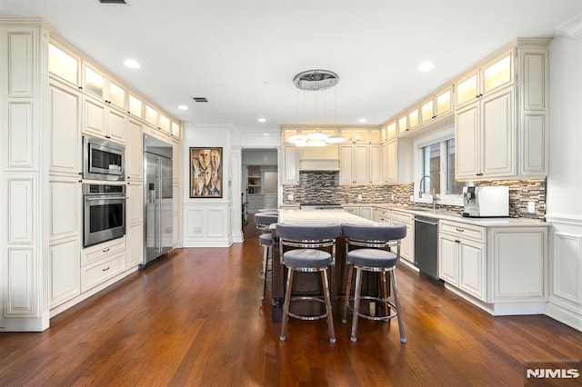 kitchen featuring built in appliances, dark hardwood / wood-style floors, decorative light fixtures, a center island, and sink