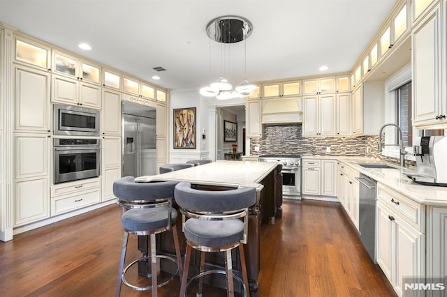 kitchen with built in appliances, sink, decorative light fixtures, and a center island