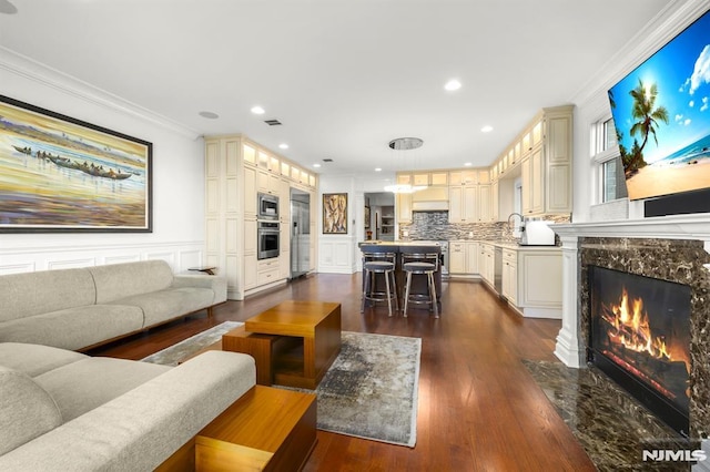 living room featuring dark wood-type flooring, a premium fireplace, crown molding, and sink