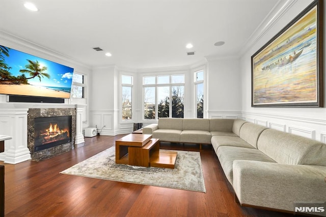 living room with crown molding, dark hardwood / wood-style flooring, and a high end fireplace