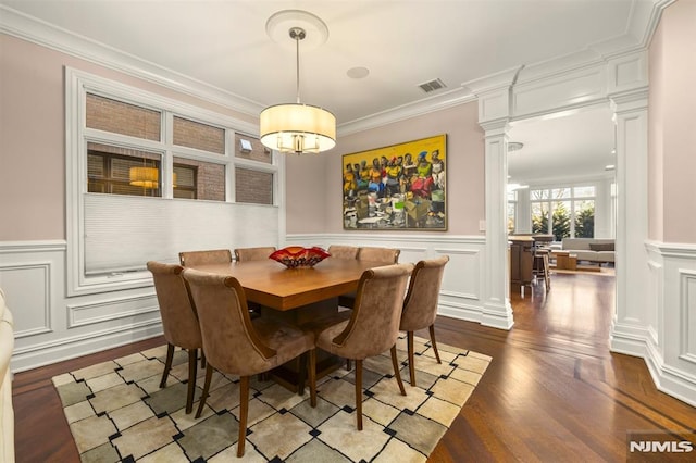 dining room with hardwood / wood-style flooring, crown molding, and ornate columns