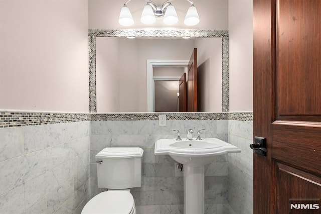 bathroom featuring tile walls and toilet