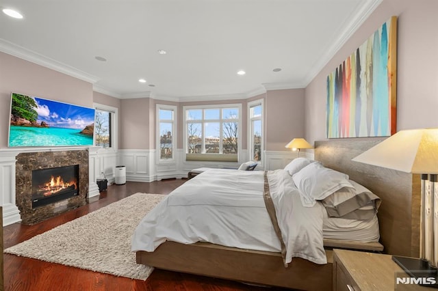 bedroom featuring a high end fireplace, crown molding, and dark hardwood / wood-style floors