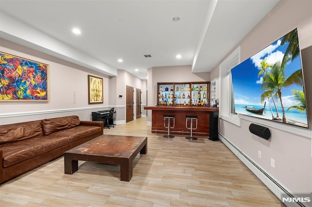 living room featuring a baseboard radiator, light wood-type flooring, and indoor bar